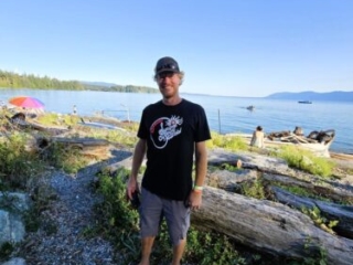 A photo of a person wearing a festival t-shirt on the beach