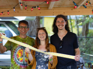 A photo of three people volunteering at the festival merch tent